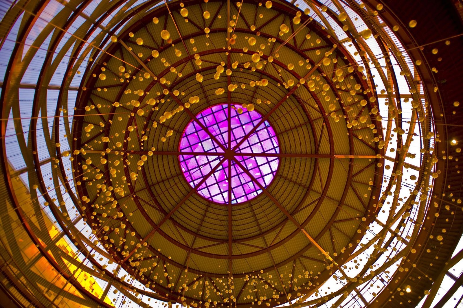 Looking up at a glowing domed ceiling with a purple center